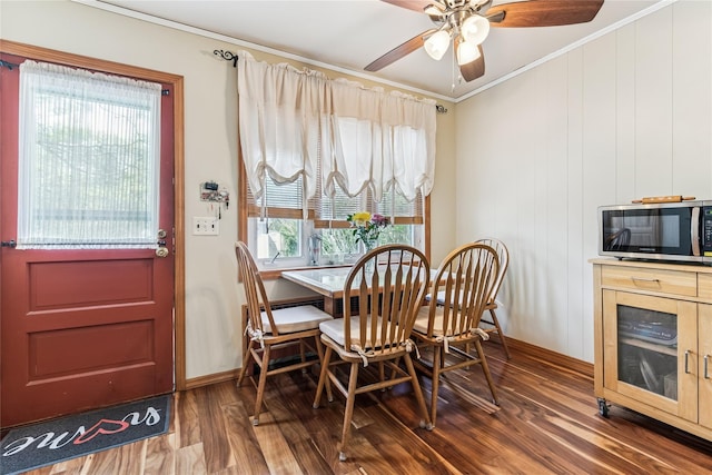 dining room featuring baseboards, ornamental molding, a ceiling fan, and wood finished floors