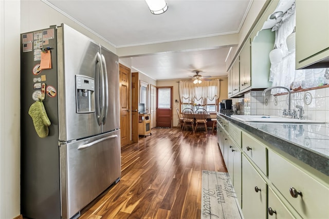 kitchen with dark wood-style flooring, stainless steel refrigerator with ice dispenser, dark countertops, and ornamental molding