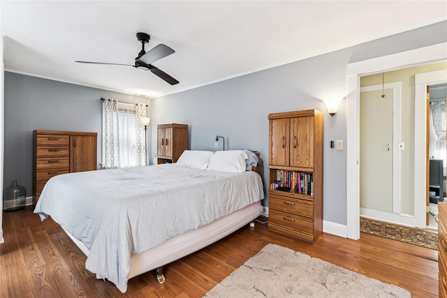 bedroom with baseboards, ceiling fan, crown molding, and wood finished floors