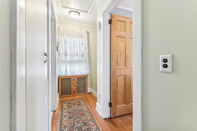 hallway featuring crown molding, baseboards, and wood finished floors