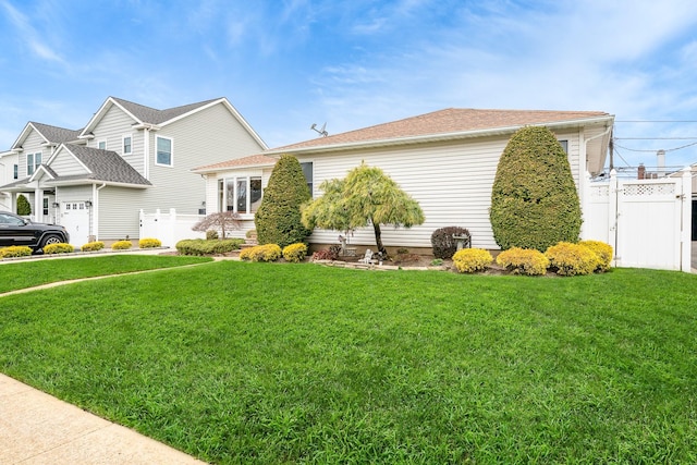 view of side of property with a yard, fence, and roof with shingles