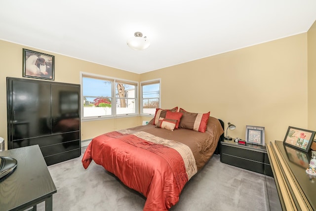 bedroom with a baseboard heating unit and light colored carpet