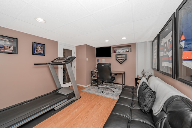 exercise room featuring wood finished floors, recessed lighting, baseboards, and a drop ceiling