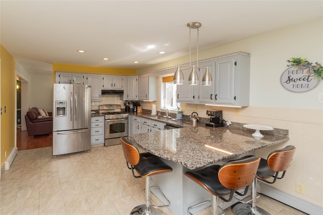 252 Southwoods Dr, Monticello, NY 12701 - kitchen with appliances with stainless steel finishes, a breakfast bar, dark stone countertops, a peninsula, and under cabinet range hood