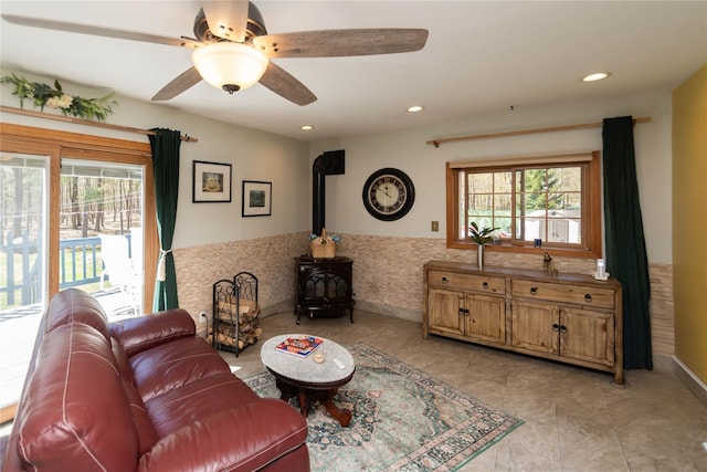 252 Southwoods Dr, Monticello, NY 12701 - living area with light tile patterned floors, a ceiling fan, a healthy amount of sunlight, and a wood stove
