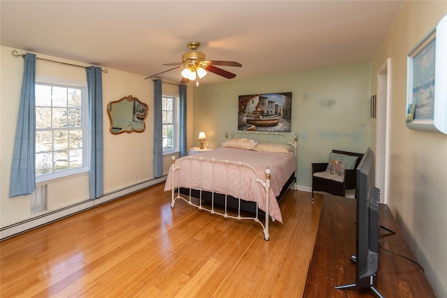 252 Southwoods Dr, Monticello, NY 12701 - bedroom featuring a ceiling fan, a baseboard heating unit, wood finished floors, and multiple windows