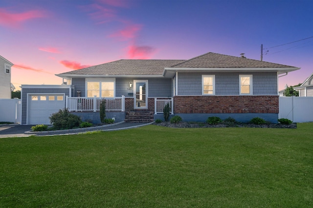 ranch-style house featuring covered porch, a lawn, a garage, brick siding, and aphalt driveway