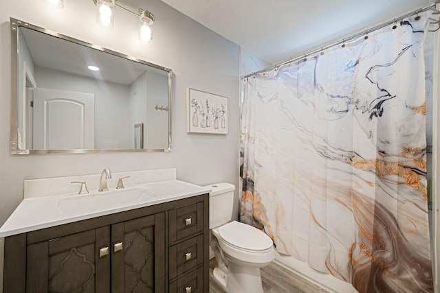 bathroom with vanity, wood finished floors, toilet, and curtained shower