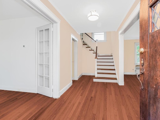 foyer entrance with baseboards, wood finished floors, and stairway