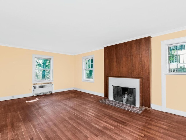 unfurnished living room with radiator, baseboards, and wood finished floors