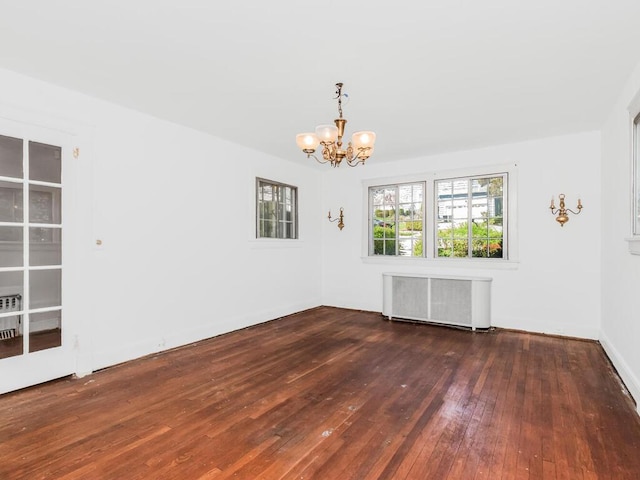 empty room featuring hardwood / wood-style flooring, an inviting chandelier, and radiator