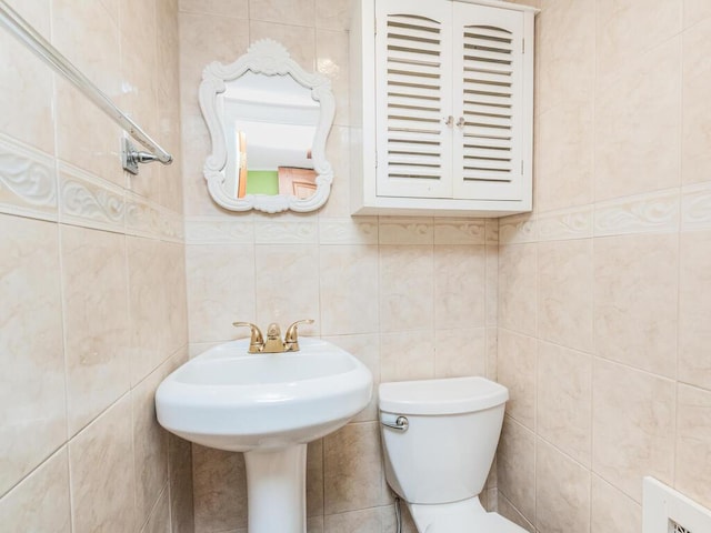 bathroom featuring toilet and tile walls