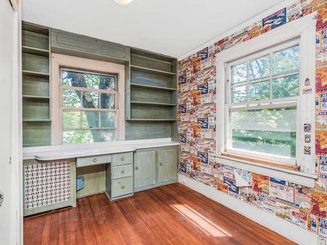 unfurnished office featuring baseboards, dark wood finished floors, a healthy amount of sunlight, and wallpapered walls