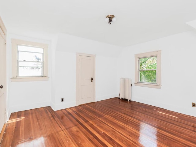 empty room featuring radiator heating unit and hardwood / wood-style floors