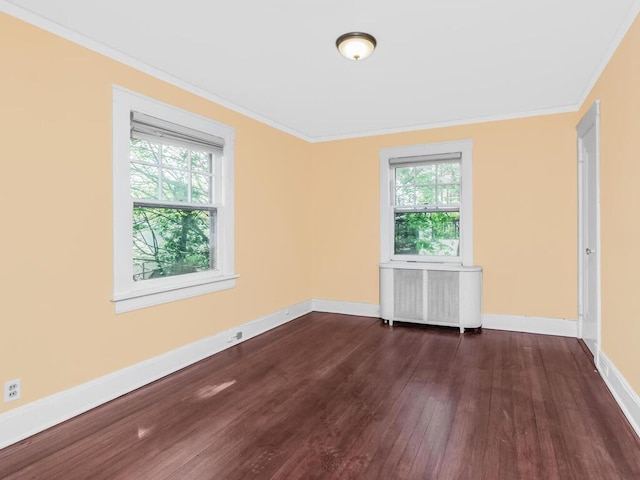 spare room featuring baseboards, ornamental molding, wood finished floors, and radiator