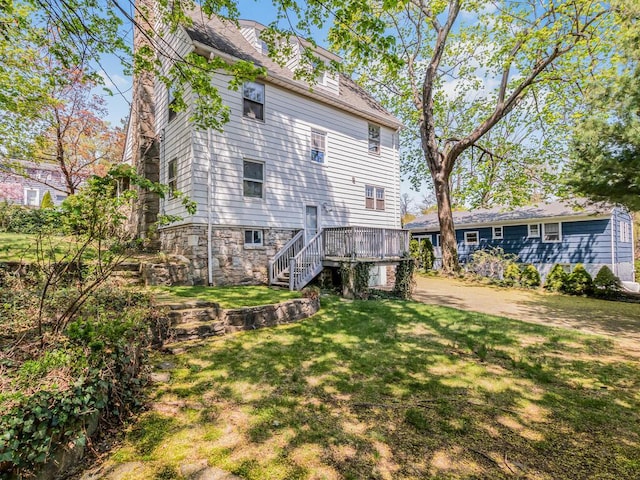 rear view of property with stairway, a lawn, and a deck
