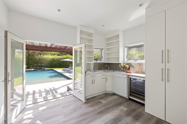 96 Audubon Ave, Bridgehampton, NY 11932 - kitchen featuring white dishwasher, beverage cooler, wood finished floors, light countertops, and tasteful backsplash
