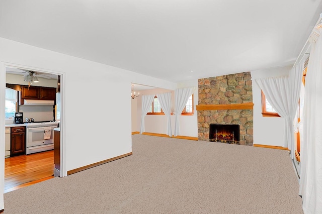 249Slosson Ave, Staten Island, NY 10314 - unfurnished living room featuring light carpet, ceiling fan with notable chandelier, baseboards, and a stone fireplace