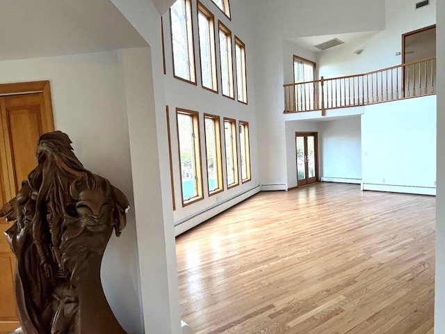 36 Ridgetop Dr, Tomkins Cove, NY 10986 - living room featuring light wood-style flooring, a towering ceiling, a baseboard radiator, and baseboards