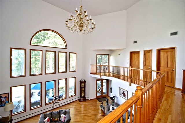 36 Ridgetop Dr, Tomkins Cove, NY 10986 - living room featuring a towering ceiling, light wood-style floors, a chandelier, baseboards, and a baseboard heating unit