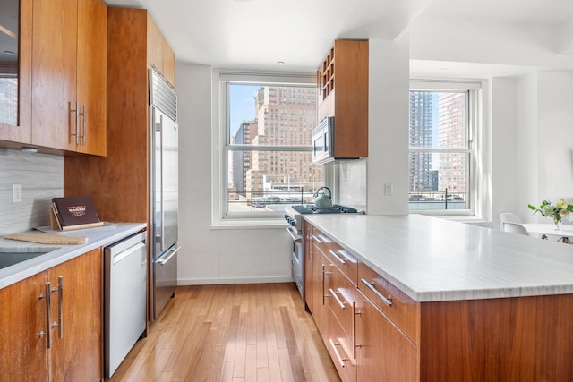 kitchen featuring a healthy amount of sunlight, brown cabinetry, and high quality appliances
