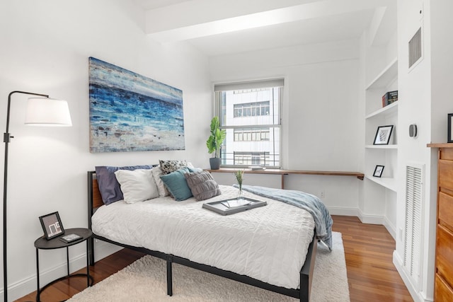 bedroom with visible vents, baseboards, and wood finished floors