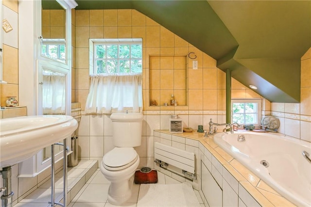 bathroom with toilet, tile patterned floors, tile walls, and plenty of natural light