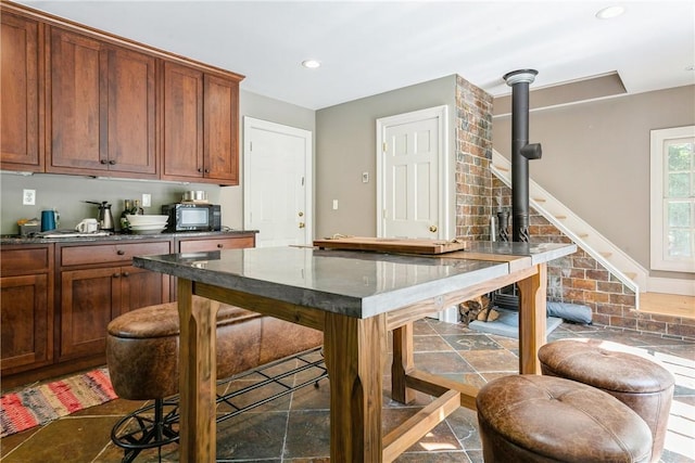 kitchen with recessed lighting, a wood stove, brown cabinets, and black microwave