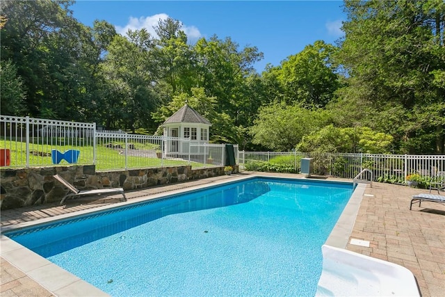 view of pool with fence, a fenced in pool, an outbuilding, and a patio area