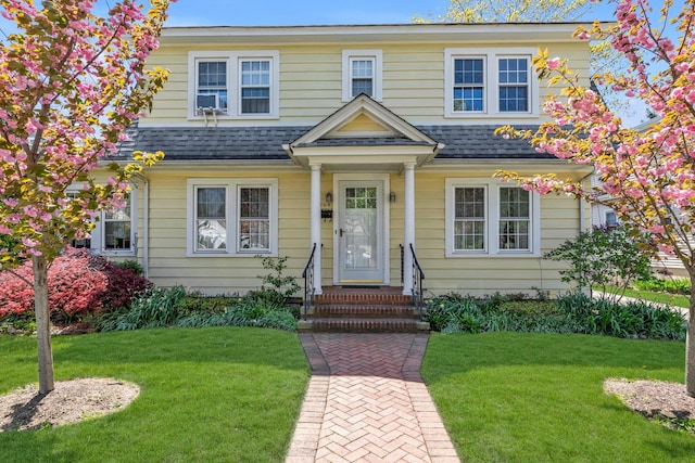 view of front facade with a front lawn and roof with shingles