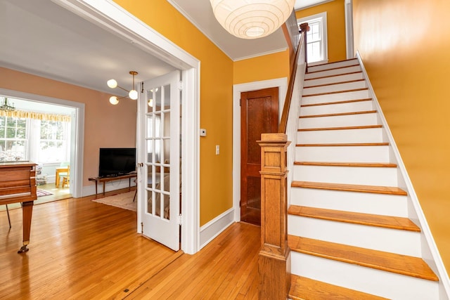 stairs with baseboards, ornamental molding, and wood-type flooring