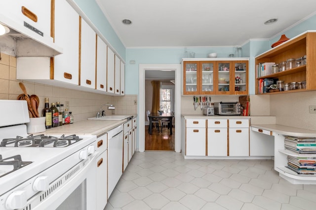 kitchen featuring a sink, white appliances, light countertops, decorative backsplash, and under cabinet range hood