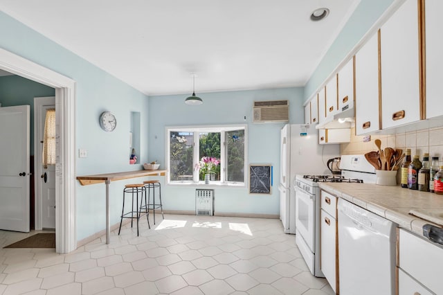 kitchen featuring a wall mounted air conditioner, backsplash, white appliances, and white cabinetry