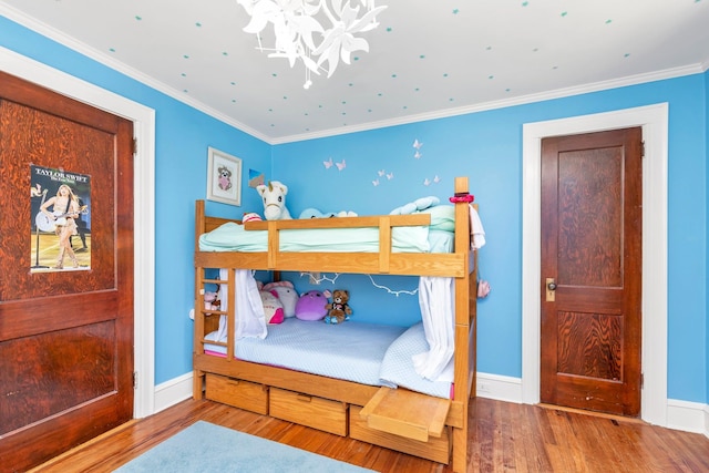 bedroom featuring baseboards, ornamental molding, wood finished floors, and a chandelier