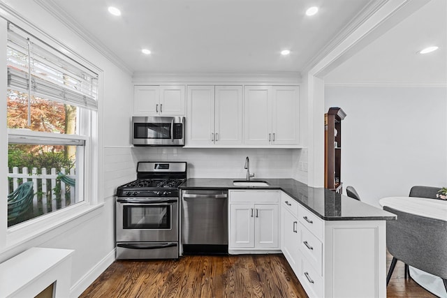 kitchen with a sink, appliances with stainless steel finishes, a peninsula, and ornamental molding