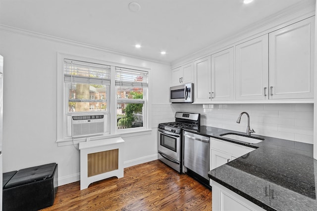 kitchen with ornamental molding, white cabinets, tasteful backsplash, a sink, and appliances with stainless steel finishes