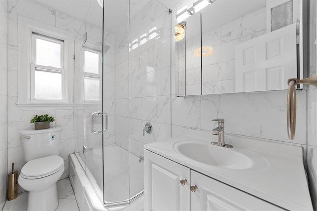 bathroom featuring vanity, marble finish floor, toilet, tile walls, and bath / shower combo with glass door