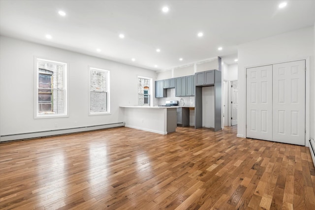 1236 Evergreen Ave, Bronx, NY 10472 - kitchen featuring a peninsula, hardwood / wood-style floors, light countertops, recessed lighting, and baseboard heating