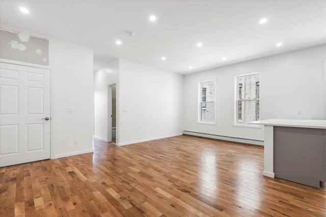 1236 Evergreen Ave, Bronx, NY 10472 - empty room featuring a baseboard heating unit, light wood finished floors, recessed lighting, and baseboards