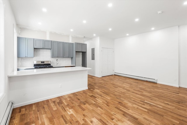 1236 Evergreen Ave, Bronx, NY 10472 - kitchen with baseboard heating, stainless steel gas range, a baseboard heating unit, tasteful backsplash, and light countertops