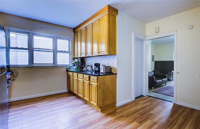 kitchen featuring light wood-style floors, dark countertops, decorative backsplash, and baseboards