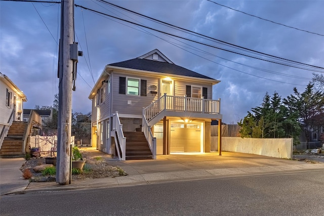 view of front of house featuring fence, stairs, an attached garage, and driveway