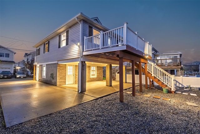 rear view of house featuring a patio, a wooden deck, stairway, and fence