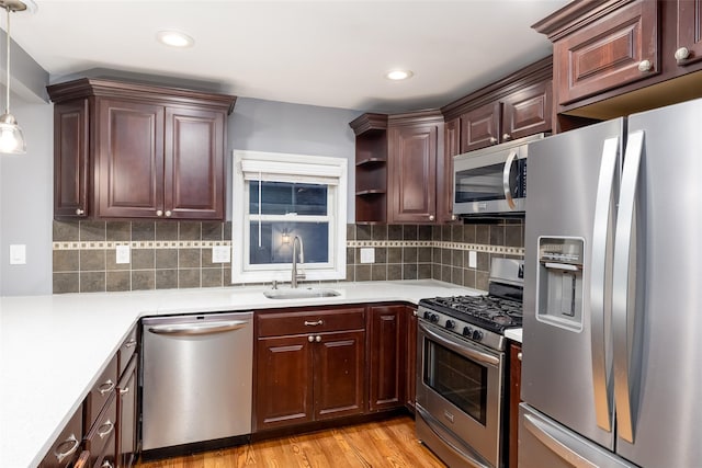 kitchen featuring decorative backsplash, a sink, light countertops, stainless steel appliances, and light wood-style flooring