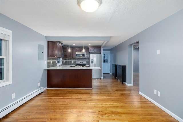 kitchen with appliances with stainless steel finishes, a sink, light countertops, a peninsula, and a baseboard heating unit