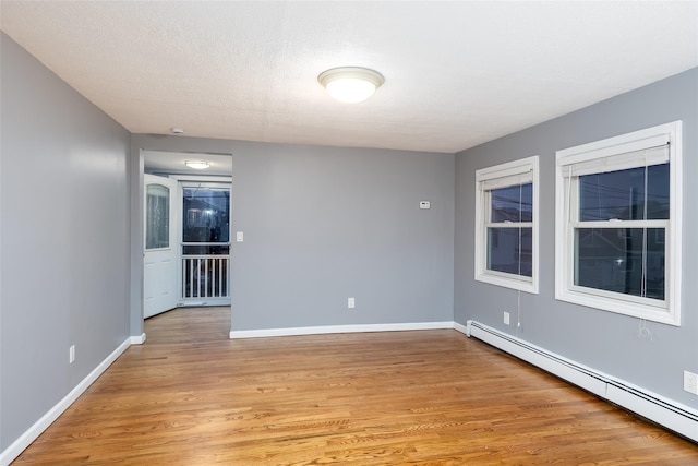 unfurnished room featuring light wood-style floors, baseboards, and a baseboard radiator