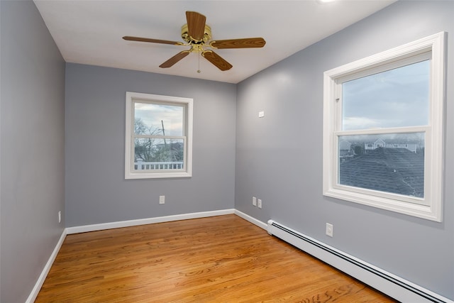 spare room with baseboards, ceiling fan, light wood finished floors, and a baseboard radiator