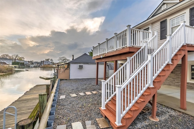 view of property exterior featuring a deck with water view, stairway, and a dock