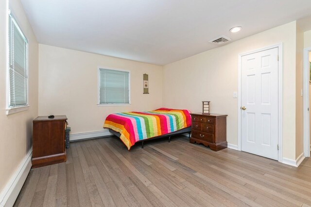 165 Tara Dr, Roslyn, NY 11576 - bedroom featuring baseboard heating, wood finished floors, a baseboard radiator, baseboards, and recessed lighting
