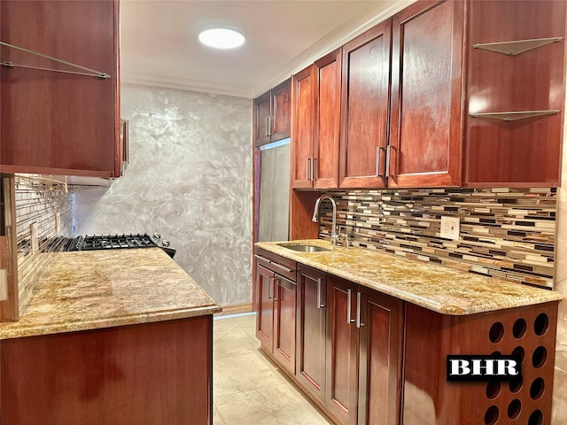 kitchen featuring light stone counters, tasteful backsplash, ornamental molding, and a sink